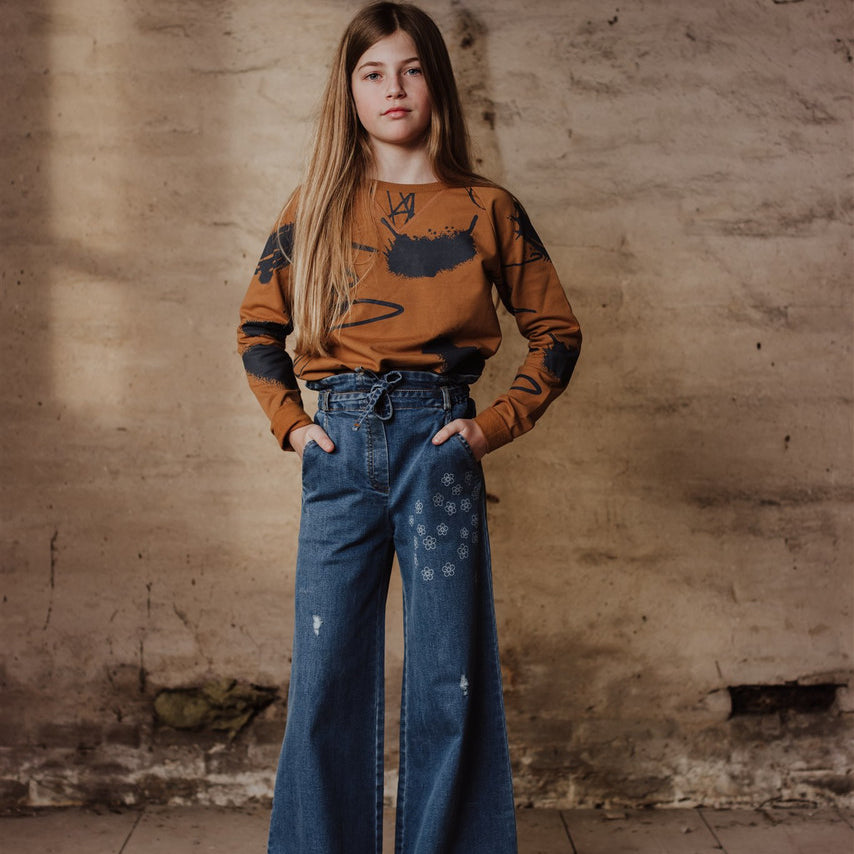 Little Hedonist high-waist wide-leg pants with elastic band in the waist. Denim authentic indigo with stitched flowers. Easy to wear and match, with a strap to finish the look. Sustainable kids clothing made form organic cotton.