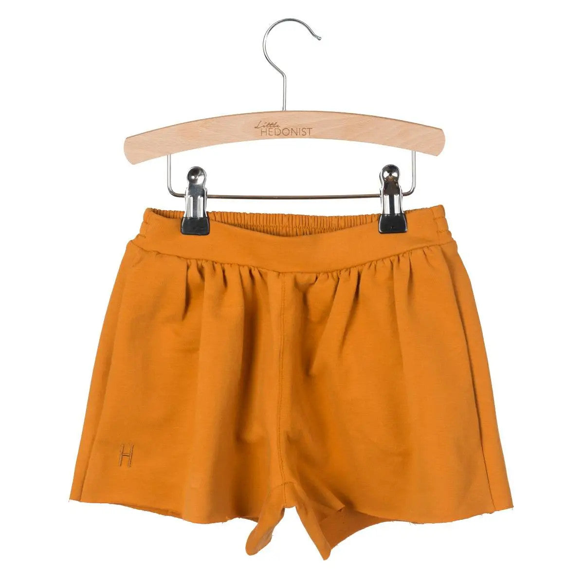 Little Hedonist organic pleated shorts with flowing cut and hidden pockets in Pumpkin Spice. Sustainable fashion for kids.